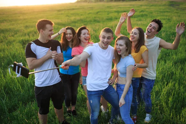 A group of joyful youth on the field is photographed on the phone