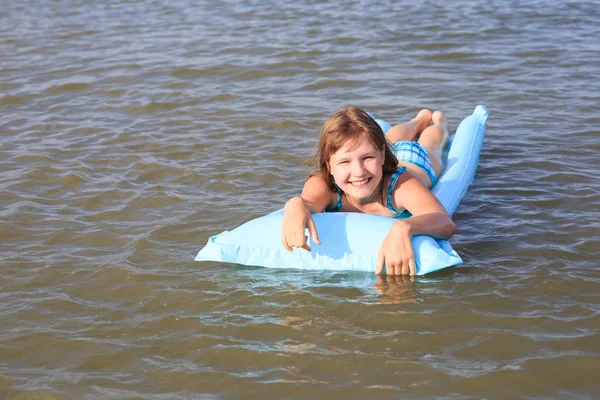 A girl of thirteen with an inflatable mattress in the sea