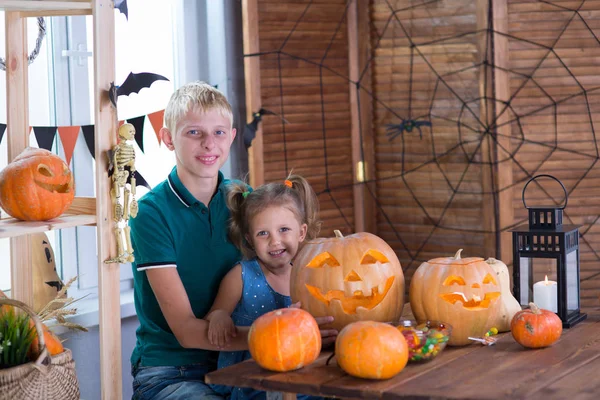 Two children on the holiday Halloween with pumpkins at the table