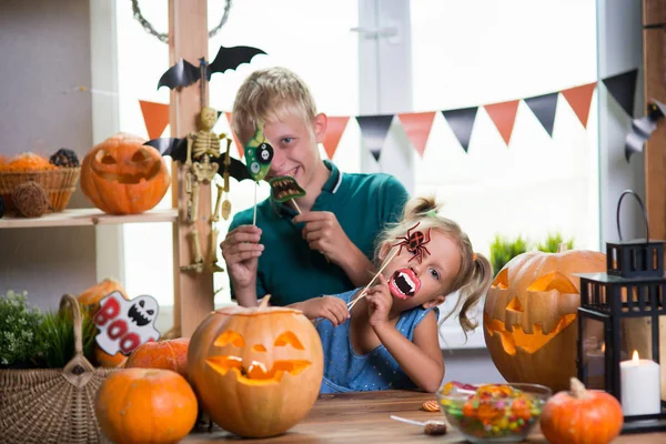 Two children on the holiday Halloween with pumpkins at the table