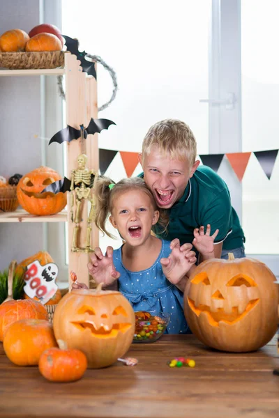 Two children on the holiday Halloween with pumpkins at the table