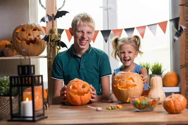 Two children on the holiday Halloween with pumpkins at the table