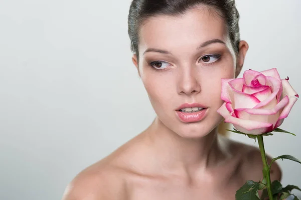 Face of beautiful young woman with rose