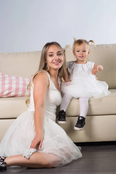 mother and daughter sitting on the couch, baby and a half years and a young woman