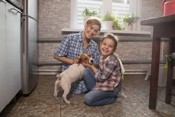 Mom and daughter play with the dog at home