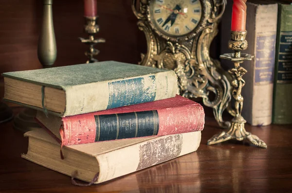 Old books on wooden table with historical clocks