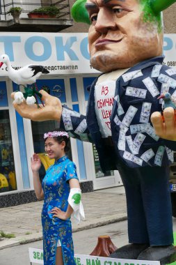 Gabrovo, Bulgaristan 19 Mayıs 2018. Geleneksel karnaval hiciv ve mizah. Sokak sanatı. Bir Mart mizahi modelleri, maskeler ve kostümler. Koreli bir kadın manken önünde bir fotoğraf çeker.