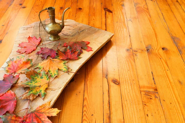 加拿大橡木的五颜六色的秋叶 木板和木地板上的一个旧铜锅 — 图库照片
