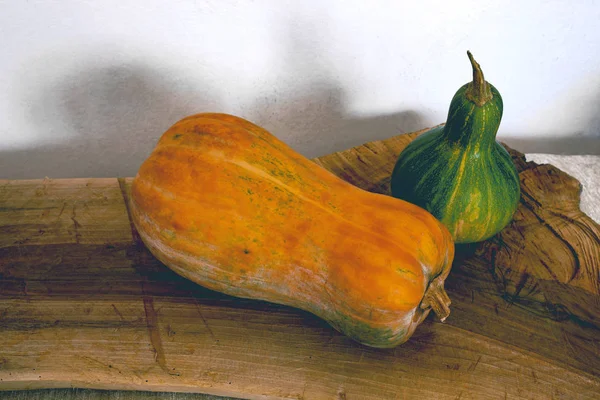 Green and yellow pumpkin from the home garden on a wooden board. Food, home. Still life.