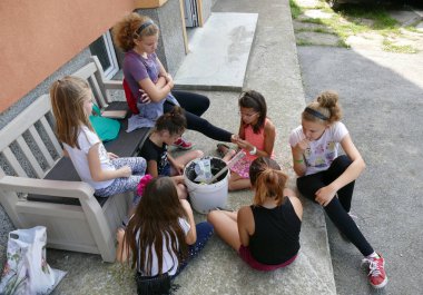 Gabrovo, Bulgaristan, 15 Temmuz 2018.Seven kız 10-12 yaş arası bir daire dışında oturup. Kabak çekirdeği yemek ve konuşmak. Yaz, tatil.