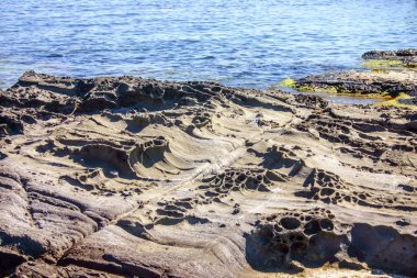 Deniz kıyısı üzerinde güzel bir uçurum. Delik ve şekilleri doğa taş heykel. Mavi deniz.
