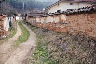 Yarı terk edilmiş bir köyde toprak yol. Bulgaristan, Doğu Avrupa. Büyük şehirlere çekilin. Köyleri terk, evler terk edilmiş ve çöktü.