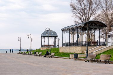 Köstence, Romanya. 19 Nisan 2019. Soğuk, karanlık Bir Nisan günü. Turistler sahil bulvarı boyunca yürürler. Köstence Karadeniz üzerinde önemli bir liman kenti yanı sıra popüler bir turizm.
