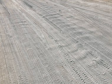 Kumlu yol. Kumsalda farklı lastik izleri var. İnsan adımları. Yakın plan fotoğraf..