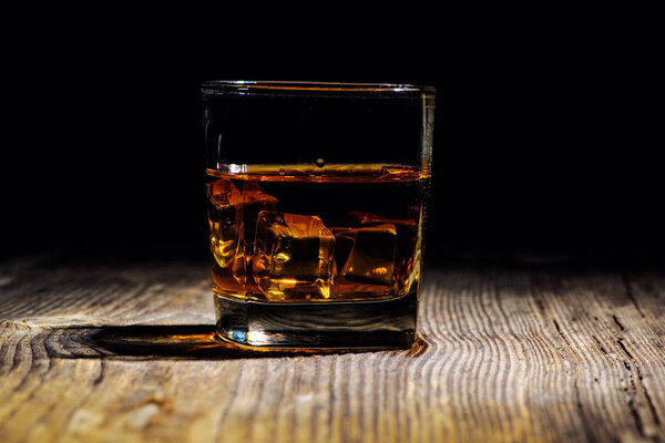 Изолированный выстрел виски с брызгами на черном фоне