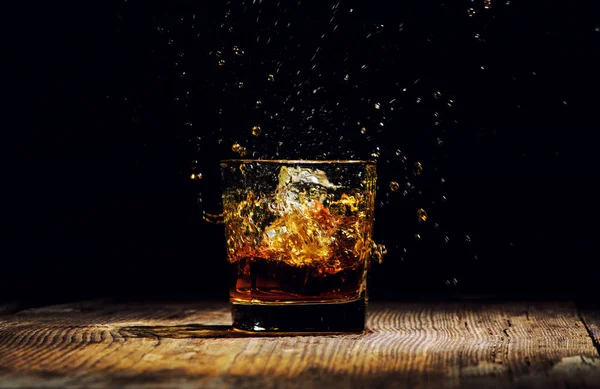 Izolovaný záběr whisky se šplouchnutím na černém pozadí — Stock fotografie