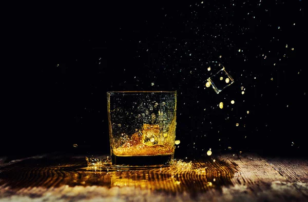 Odizolowany kieliszek whisky z pluskiem na czarnym tle — Zdjęcie stockowe