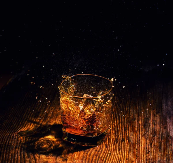 Whiskey with ice cubes on wooden background — Stock Photo, Image