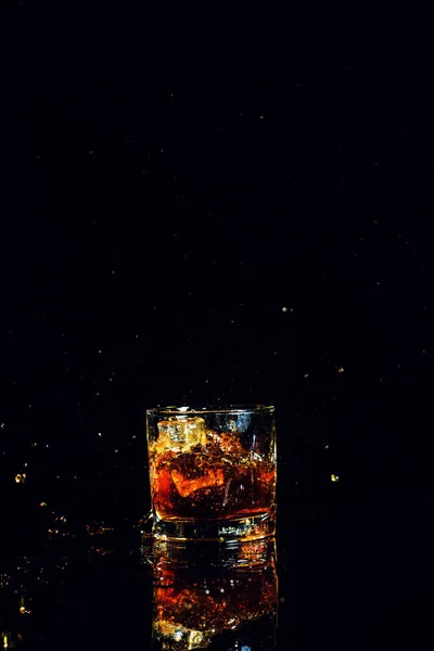 Изолированный выстрел виски с брызгами на черном фоне — стоковое фото
