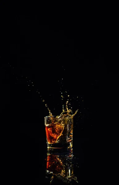 Geïsoleerde shot whisky met splash op zwarte achtergrond — Stockfoto