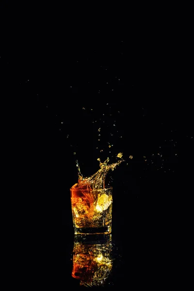 Geïsoleerde shot whisky met splash op zwarte achtergrond — Stockfoto