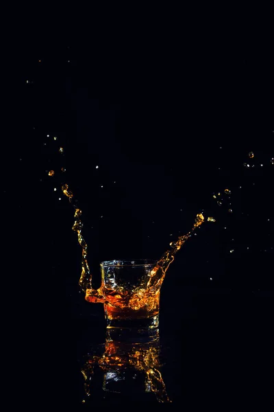 Isolated shot of whiskey with splash on black background — Stock Photo, Image