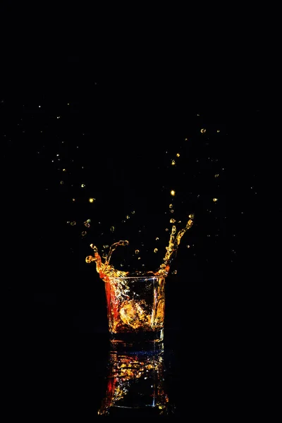 Whisky mit Spritzer auf schwarzem Hintergrund, Brandy im Glas — Stockfoto