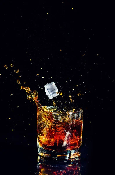 Isolierter Schuss Whisky mit Spritzer auf schwarzem Hintergrund — Stockfoto