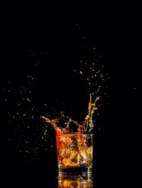 Whisky mit Spritzer auf schwarzem Hintergrund, Brandy im Glas — Stockfoto