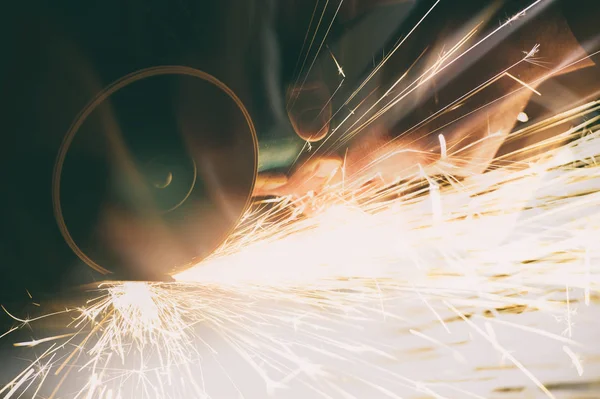 Metal grinding on steel pipe with flash of sparks close up — Stock Photo, Image