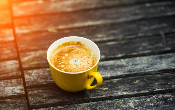 Secangkir kopi kuning lezat, dengan latar belakang meja kayu pedesaan . — Stok Foto