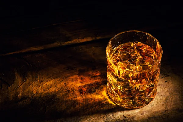 Whiskey with ice cubes on wooden background — Stock Photo, Image