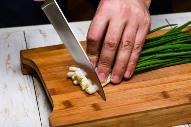 Yemek. Şef mutfakta yeşil soğan kesiyor