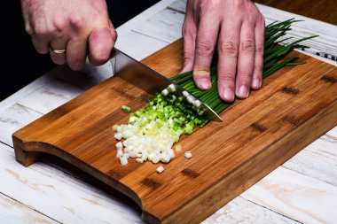 Yemek. Şef mutfakta yeşil soğan kesiyor