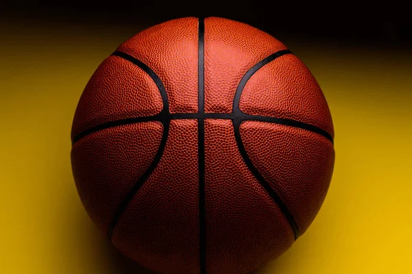 Piłkę do koszykówki na żółtym tle. — Zdjęcie stockowe