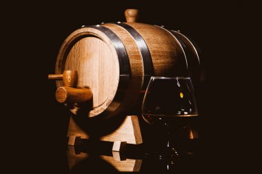 Siyah arka plan üzerinde meşe varil ile konyak cam. Ahşap barr