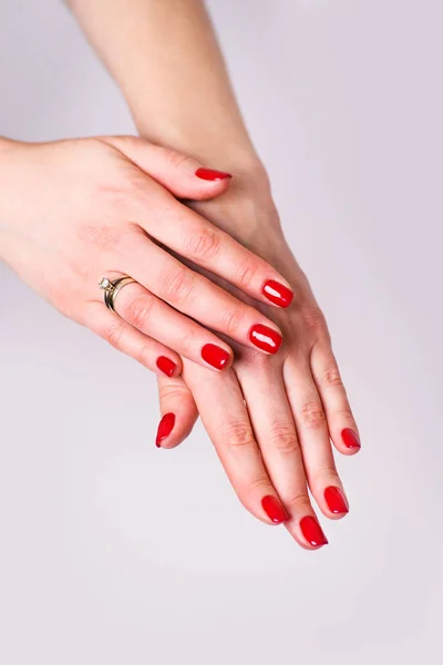 Diseño de uñas. Manos con manicura de primavera roja brillante en la espalda gris — Foto de Stock