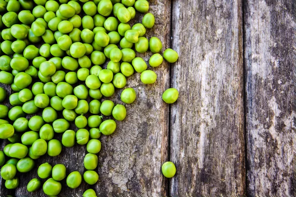 Grüne Erbsen auf Holzgrund. Gesunde Ernährung. dunkler rustikaler Stil — Stockfoto