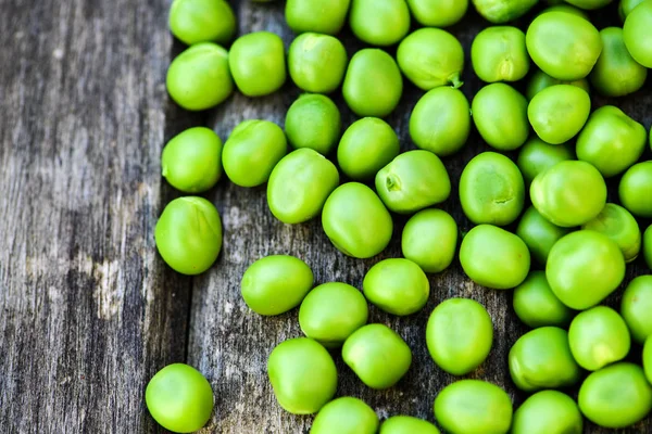 Grüne Erbsen auf Holzgrund. Gesunde Ernährung. dunkler rustikaler Stil — Stockfoto