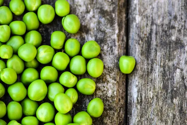 Grüne Erbsen auf Holzgrund. Gesunde Ernährung. dunkler rustikaler Stil — Stockfoto