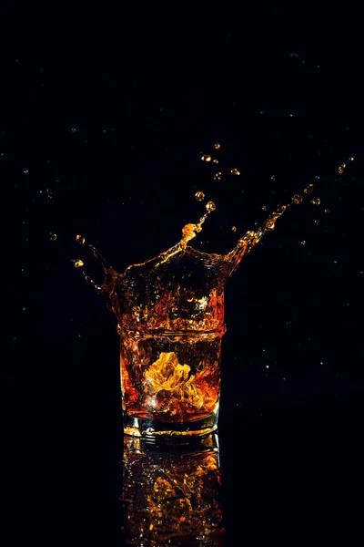 Isolated shot of whiskey with splash on black background — Stock Photo, Image