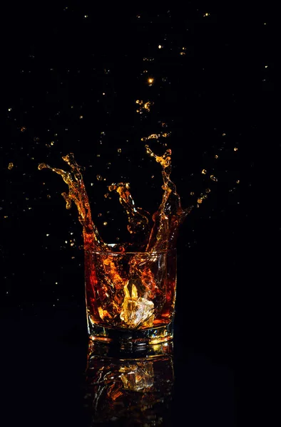 Geïsoleerde shot whisky met splash op zwarte achtergrond — Stockfoto