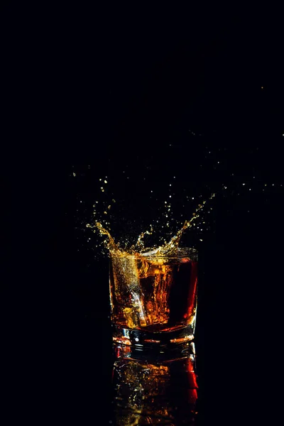 Isolierter Schuss Whisky mit Spritzer auf schwarzem Hintergrund — Stockfoto