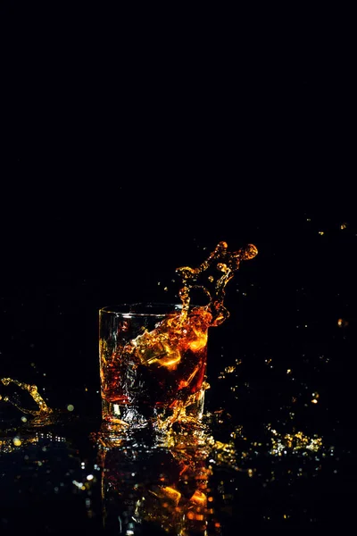 Tiro aislado de whisky con salpicadura sobre fondo negro — Foto de Stock