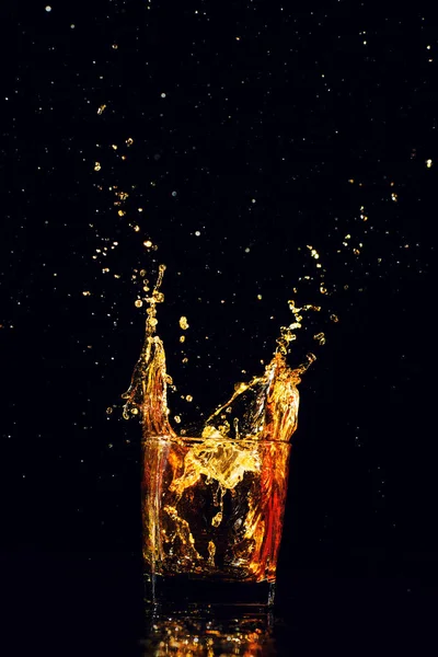 Isolated shot of whiskey with splash on black background — Stock Photo, Image