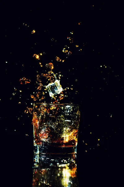 Izolovaný záběr whisky se šplouchnutím na černém pozadí — Stock fotografie