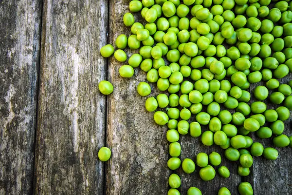 Grüne Erbsen auf Holzgrund — Stockfoto