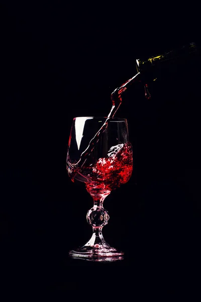 Red wine pouring into wine glass with splash, isolated on black — 스톡 사진