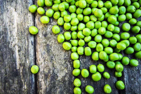 Ervilhas verdes em fundo de madeira — Fotografia de Stock