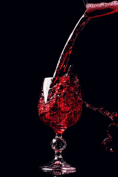 Red wine pouring into wine glass with splash, isolated on black — 스톡 사진